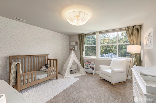 carpeted bedroom featuring wallpapered walls, baseboards, visible vents, and a nursery area