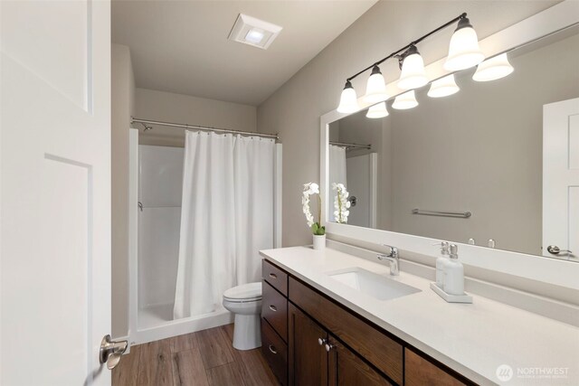 full bathroom with wood finished floors, curtained shower, vanity, and toilet