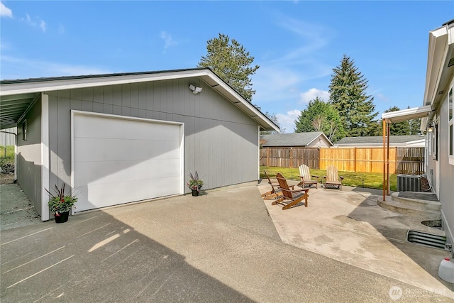 garage with fence, driveway, and cooling unit
