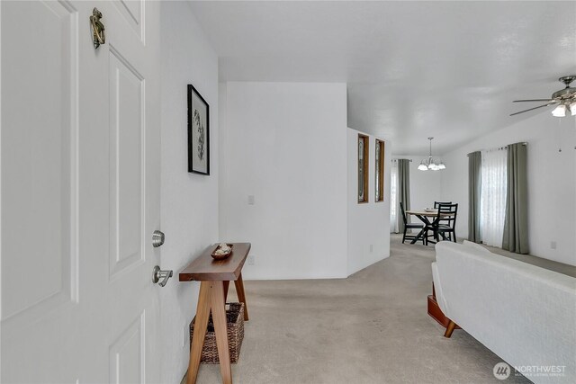foyer with light carpet, a ceiling fan, and a chandelier