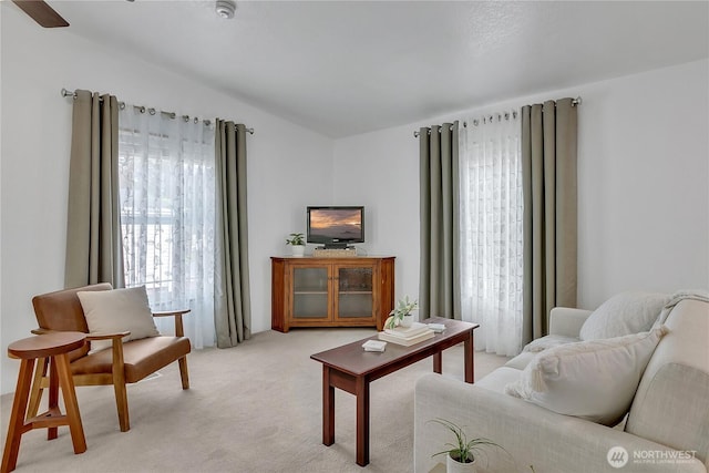 living area featuring light carpet and ceiling fan