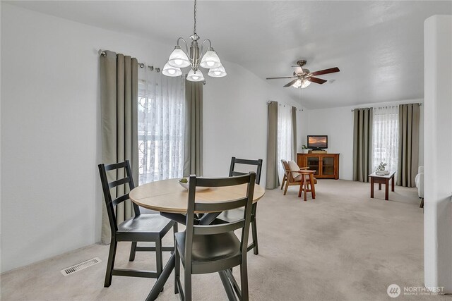 dining area with a chandelier, light colored carpet, and ceiling fan