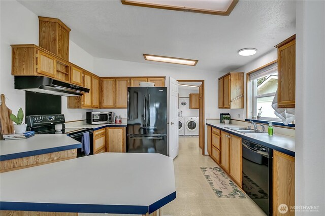 kitchen with black appliances, under cabinet range hood, washing machine and dryer, a sink, and a peninsula