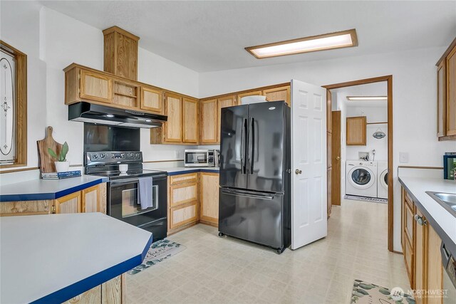 kitchen with black appliances, under cabinet range hood, separate washer and dryer, light countertops, and light flooring
