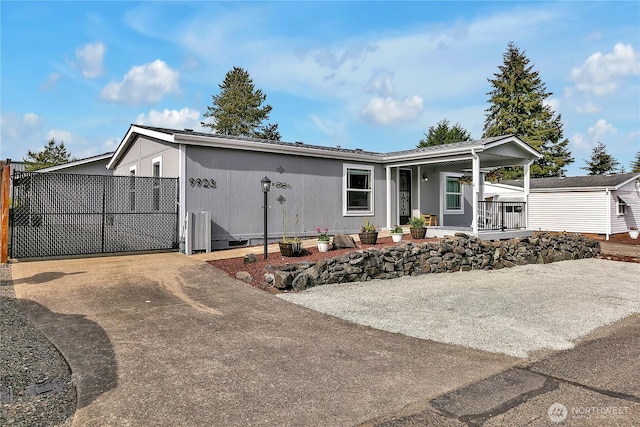 view of front of home featuring a porch, concrete driveway, and fence