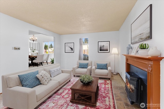 living room with a textured ceiling, a chandelier, and a wood stove
