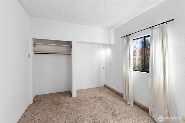 unfurnished bedroom with a textured ceiling, a closet, and light carpet