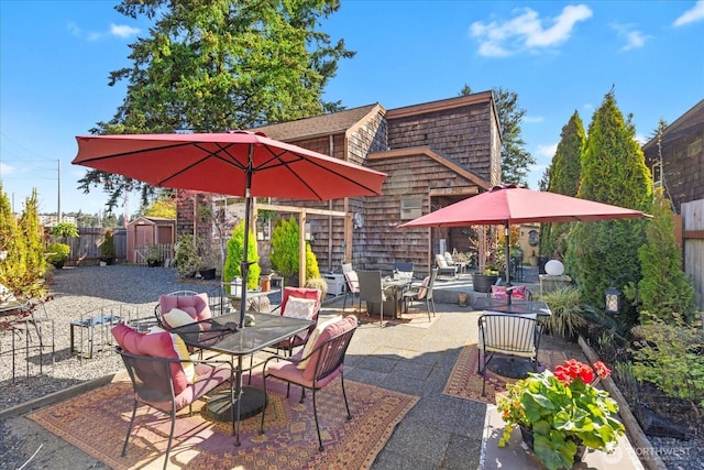 view of patio featuring outdoor dining area, an outdoor structure, a storage unit, and a fenced backyard