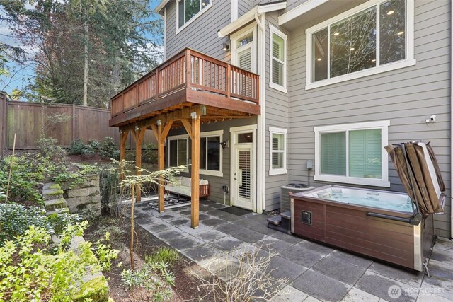 rear view of property with central AC unit, fence, a wooden deck, a patio area, and a hot tub