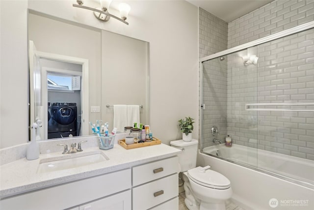 full bathroom featuring vanity, toilet, bath / shower combo with glass door, and washer / clothes dryer