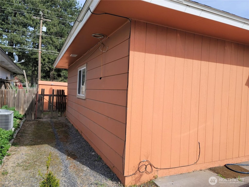 view of side of home with central AC and fence