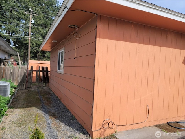 view of side of home with central AC and fence