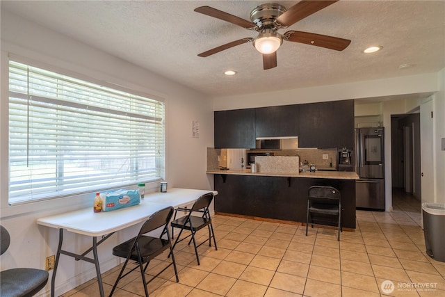 775 S 4th Ave, Othello, WA 99344 - kitchen with stainless steel fridge, a kitchen breakfast bar, light countertops, a peninsula, and a textured ceiling
