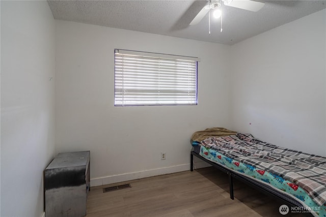 775 S 4th Ave, Othello, WA 99344 - unfurnished bedroom with wood finished floors, baseboards, a ceiling fan, and a textured ceiling