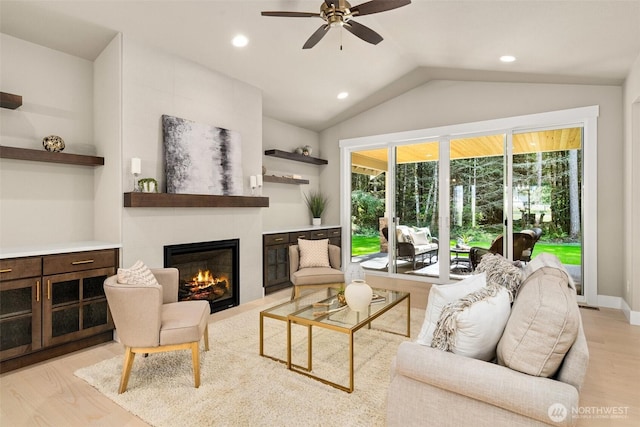 living area with ceiling fan, a large fireplace, light wood-style floors, lofted ceiling, and recessed lighting