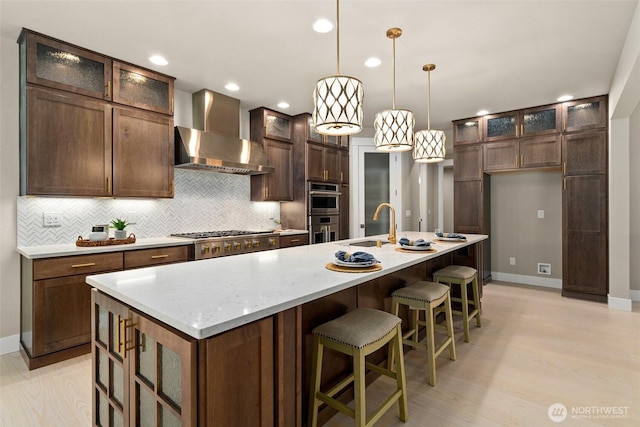 kitchen with stainless steel appliances, wall chimney range hood, tasteful backsplash, and recessed lighting