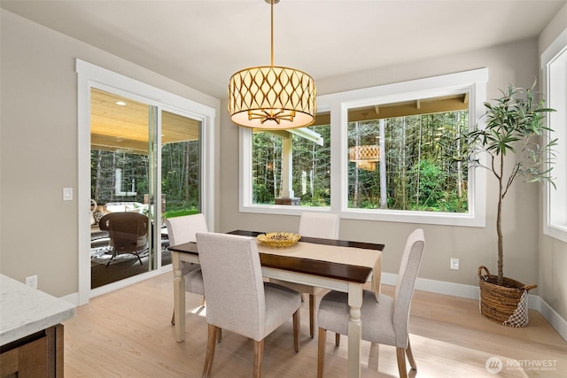 dining space featuring light wood-style floors and baseboards