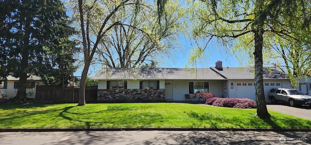 ranch-style house featuring fence, a front lawn, driveway, and an attached garage