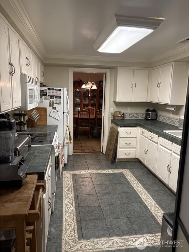kitchen with a chandelier, range with electric cooktop, white microwave, white cabinetry, and ornamental molding
