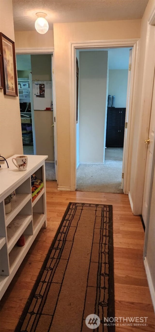 corridor featuring light wood-style flooring and baseboards