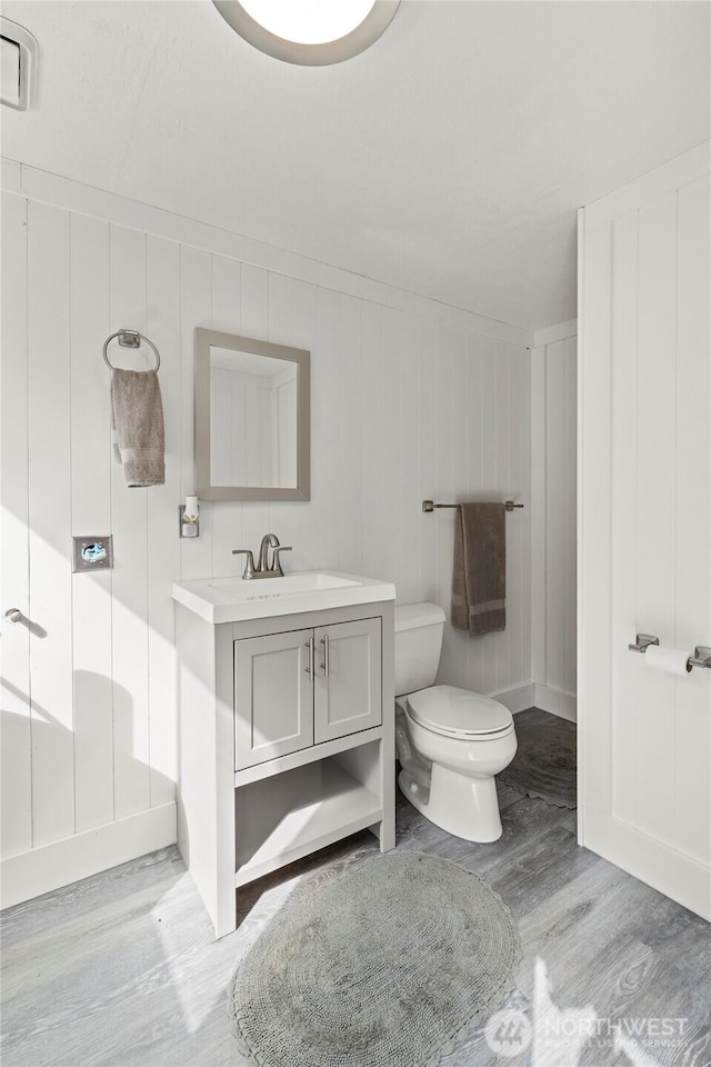 243 Porter Creek Rd, Elma, WA 98541 - bathroom featuring wood finished floors, a decorative wall, toilet, and vanity
