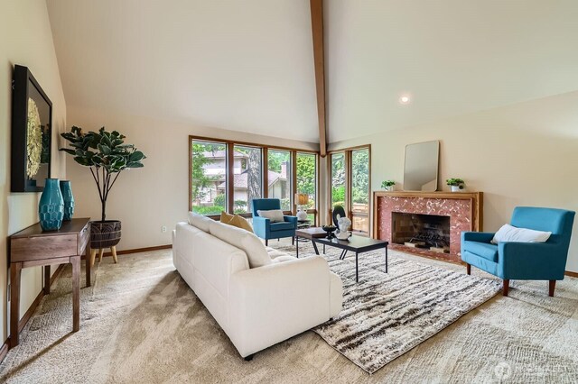 living area with beam ceiling, baseboards, a high end fireplace, light carpet, and high vaulted ceiling