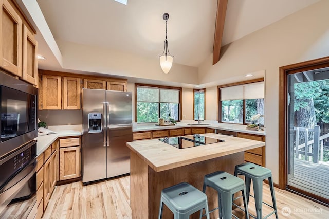 kitchen featuring stainless steel refrigerator with ice dispenser, butcher block countertops, black electric cooktop, a kitchen breakfast bar, and light wood finished floors
