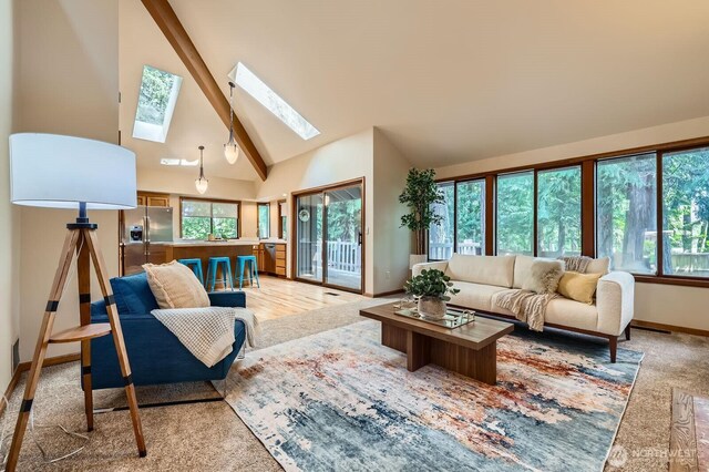 living area featuring baseboards, a skylight, beamed ceiling, high vaulted ceiling, and light carpet