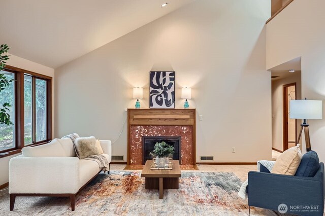 living room with high vaulted ceiling, a high end fireplace, and baseboards