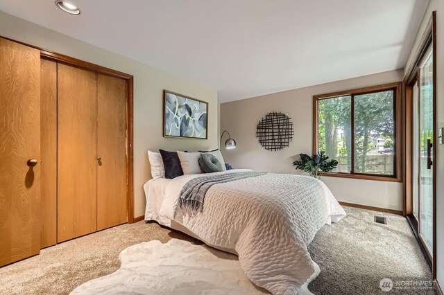 bedroom featuring light colored carpet, a closet, and baseboards