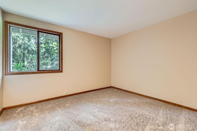 carpeted empty room featuring baseboards