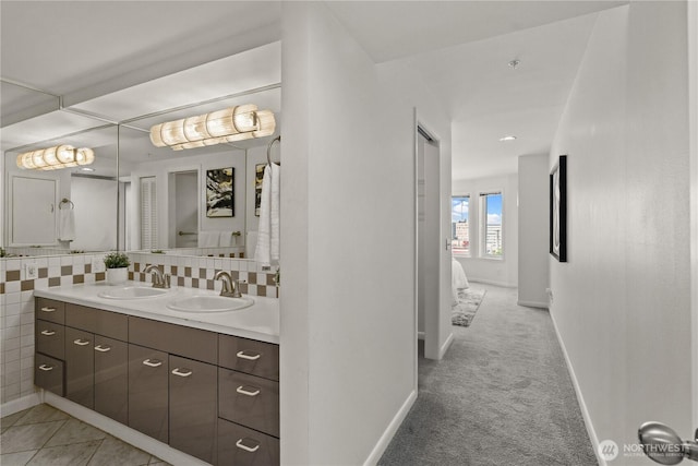 bathroom featuring ensuite bath, vanity, tasteful backsplash, and baseboards