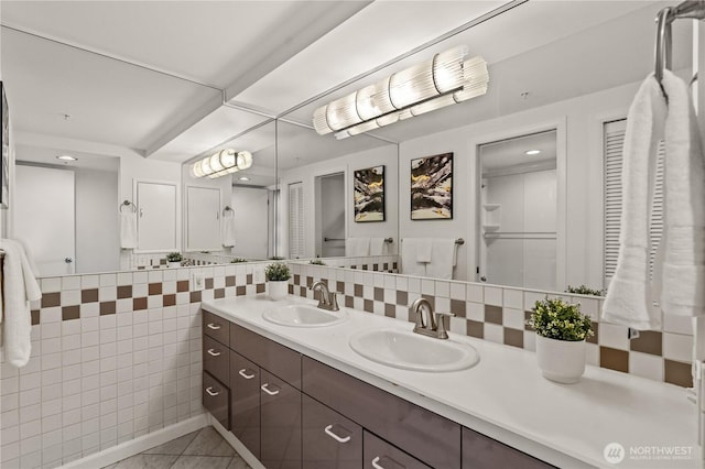 full bath with double vanity, decorative backsplash, tile patterned flooring, and a sink