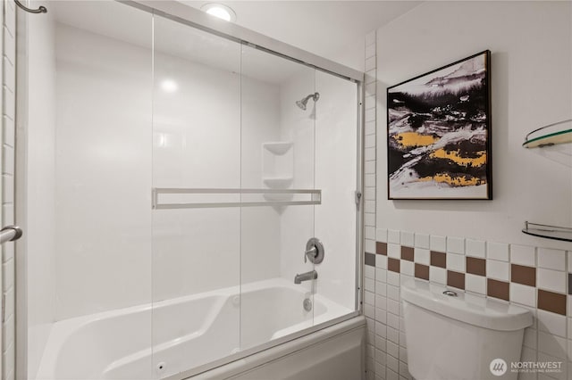 full bathroom with toilet, tile walls, and bath / shower combo with glass door