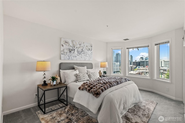 carpeted bedroom featuring a city view, baseboards, and visible vents