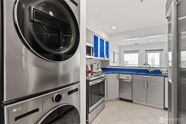 clothes washing area featuring stacked washer / drying machine, a sink, laundry area, visible vents, and recessed lighting