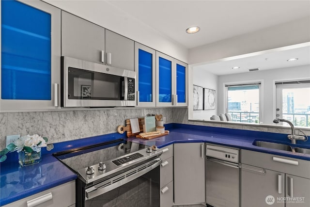kitchen with dark countertops, tasteful backsplash, appliances with stainless steel finishes, and a sink