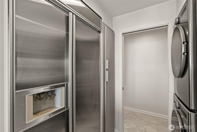 interior space featuring baseboards, marble finish floor, and stacked washer / dryer