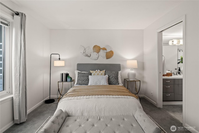 carpeted bedroom with ensuite bathroom and baseboards