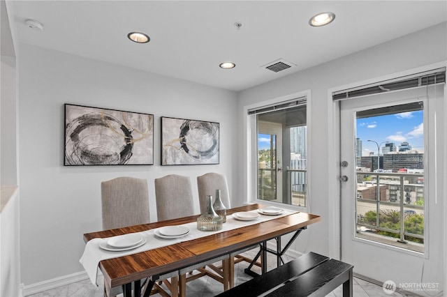 dining space with recessed lighting, baseboards, marble finish floor, a view of city, and visible vents