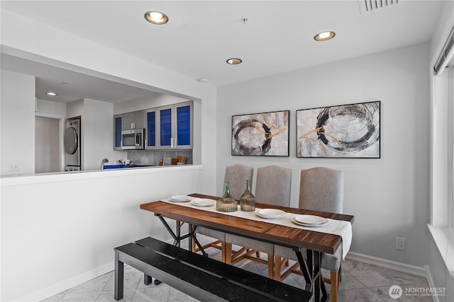 dining area with recessed lighting, baseboards, marble finish floor, visible vents, and stacked washer and clothes dryer