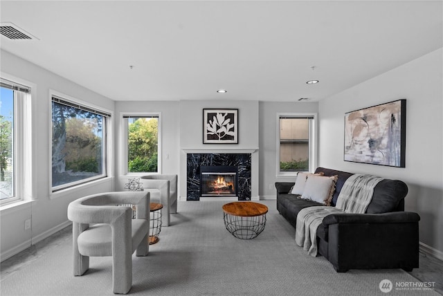 living room with visible vents, baseboards, a premium fireplace, and recessed lighting