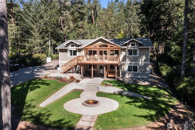 back of property with a fire pit, a yard, a wooden deck, and stairs