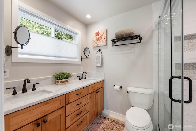 bathroom featuring toilet, a shower stall, and a sink