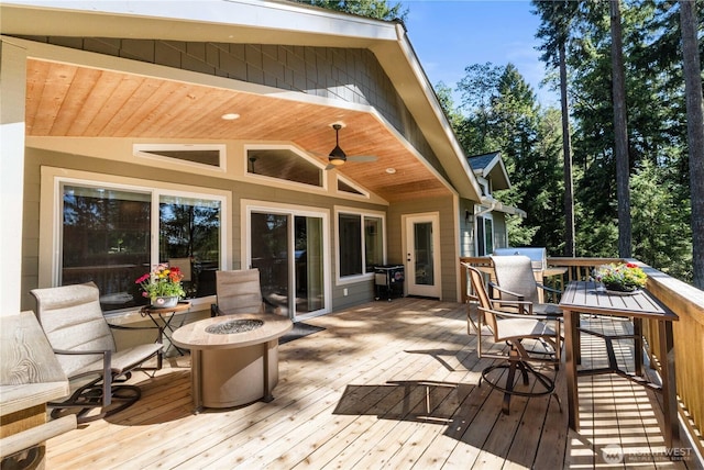 deck with outdoor dining area, a fire pit, and ceiling fan