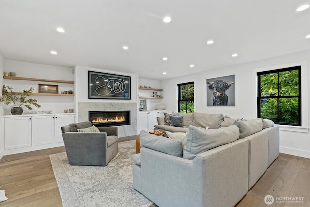 living area with baseboards, recessed lighting, wood finished floors, and a premium fireplace