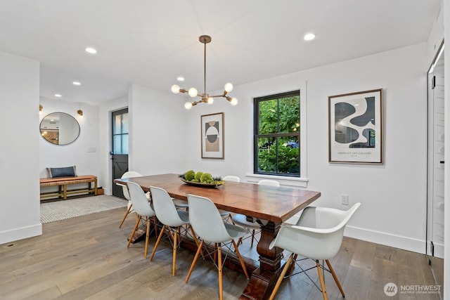dining space with baseboards, wood finished floors, recessed lighting, and a chandelier
