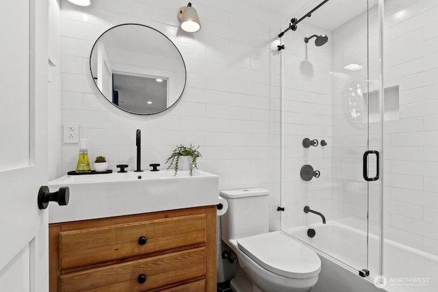 bathroom featuring tile walls, vanity, enclosed tub / shower combo, and toilet
