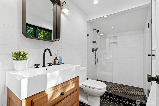 bathroom with recessed lighting, a tile shower, toilet, and vanity