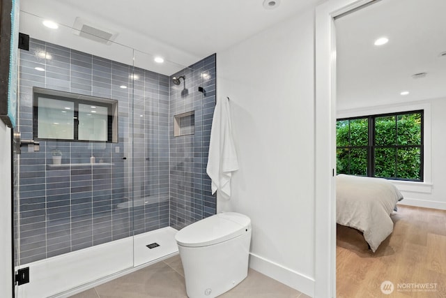 ensuite bathroom featuring toilet, wood finished floors, tiled shower, baseboards, and recessed lighting